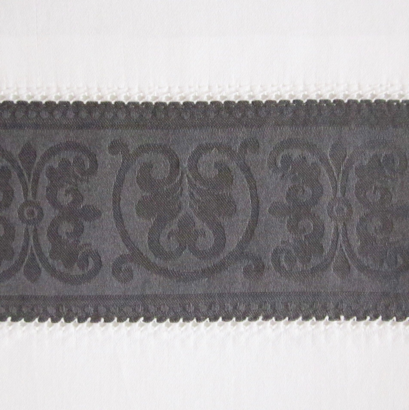 Close-up of charcoal woven jacquard border trim with ornate scrollwork detail.