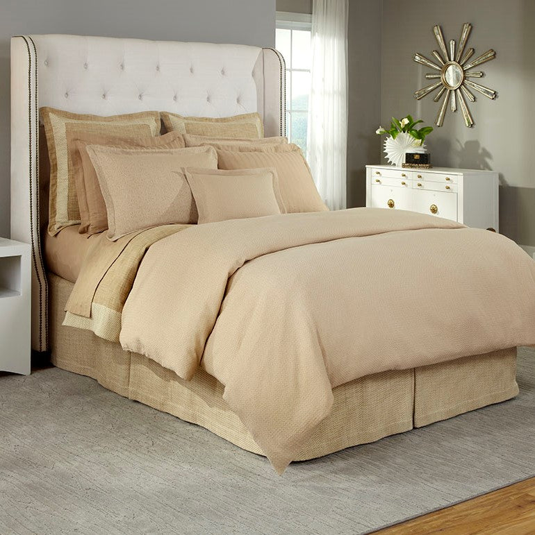 Champagne matelassé duvet cover and shams styled on a bed with ivory tufted headboard.
