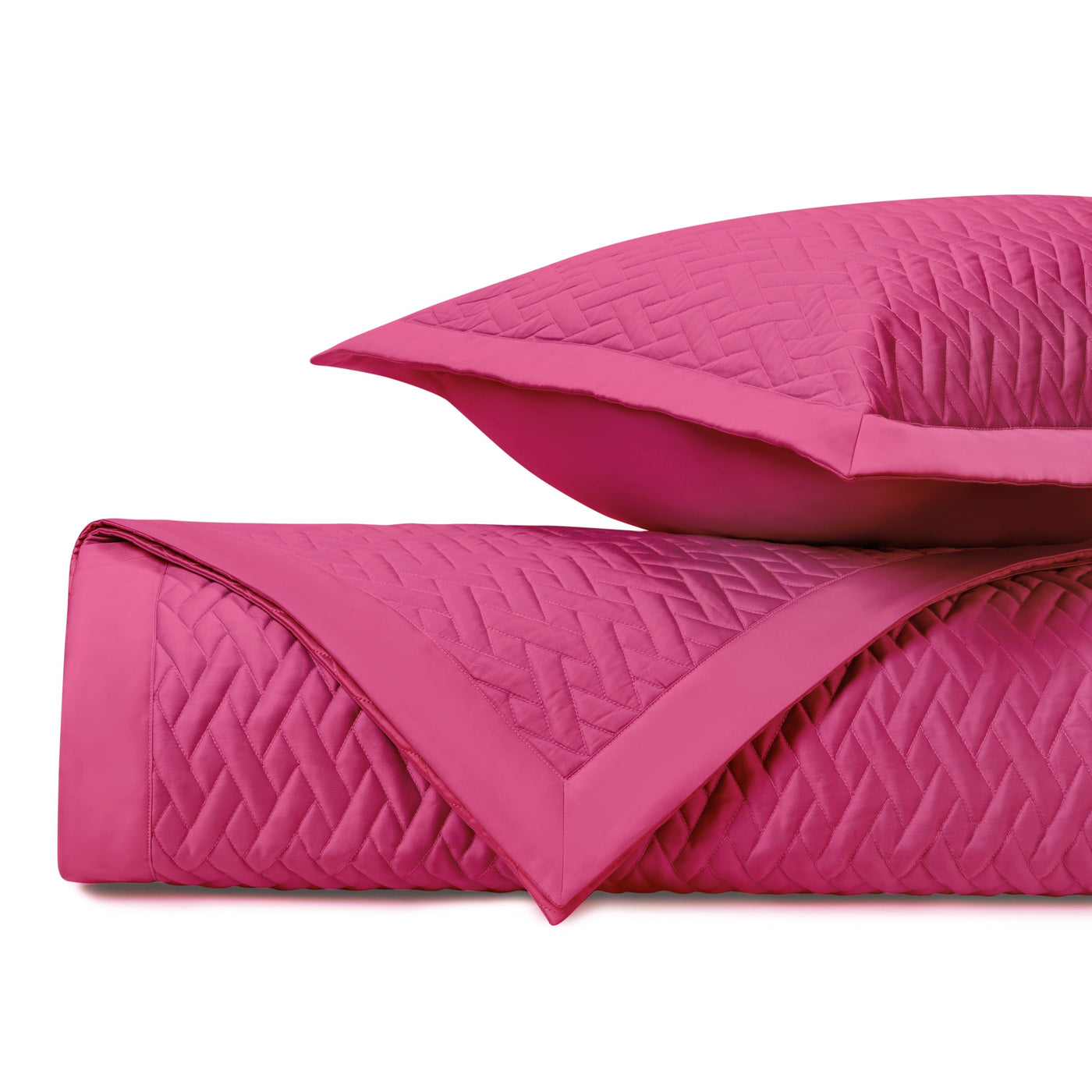 Fuchsia quilted coverlet rolled and stacked with matching euro sham, showing diamond stitching detail.