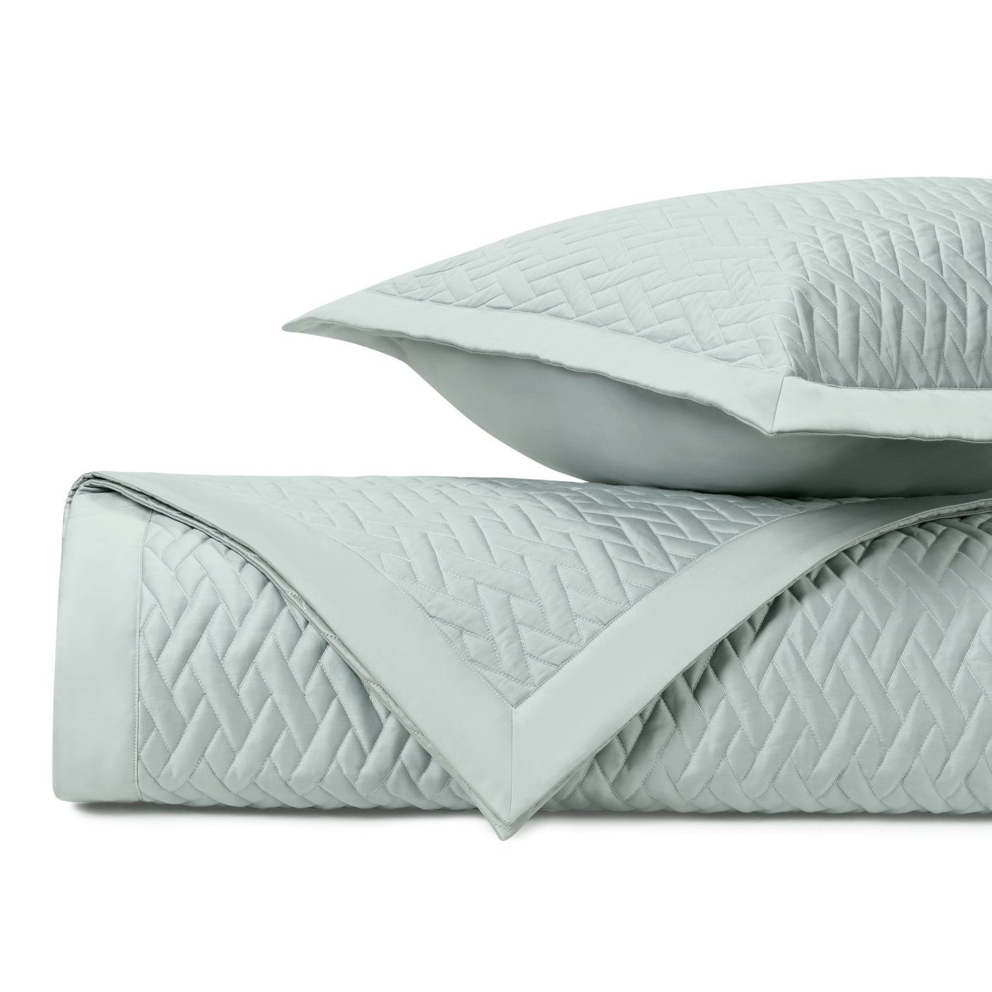 Close-up of seafoam quilted yardage with diamond lattice stitching, folded with matching sham.