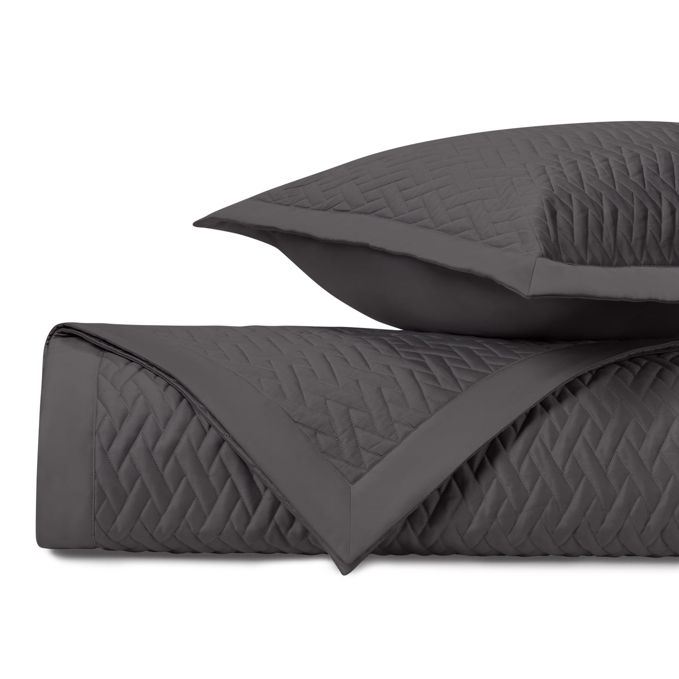 Close-up of charcoal quilted coverlet and sham showing geometric diamond stitching detail.