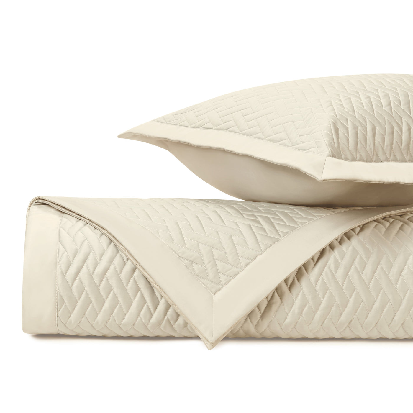 Close-up of ivory quilted coverlet and sham showing diamond stitching pattern and border detail.