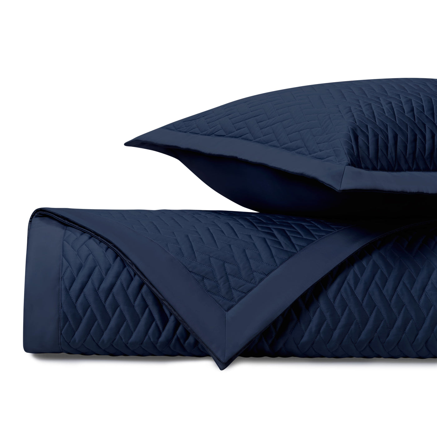 Close-up of navy blue quilted coverlet with diamond stitching pattern and coordinating sham.