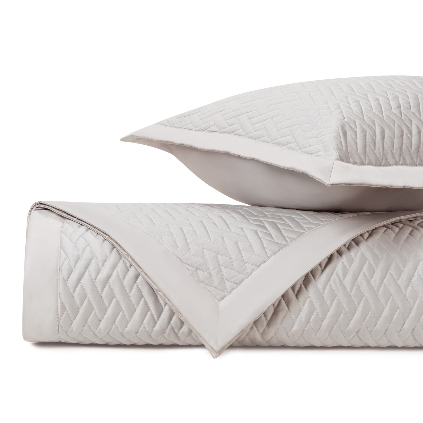 Close-up of ivory quilted coverlet with geometric diamond stitching and matching sham.