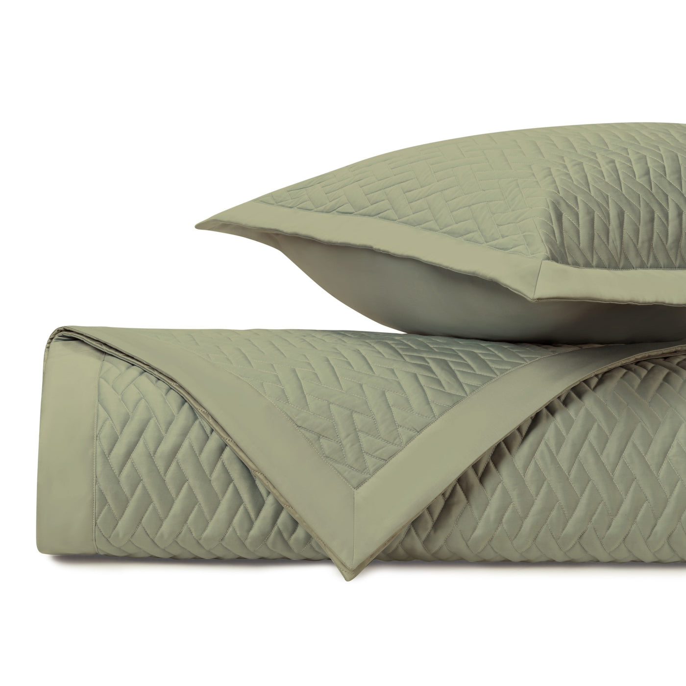 Close-up of sage green quilted coverlet with woven diamond pattern and matching sham.