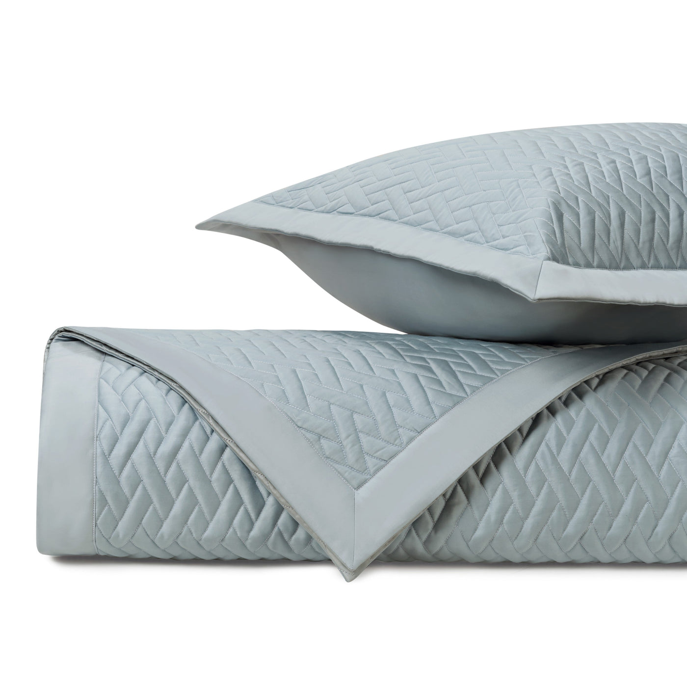 Close-up of mist blue quilted coverlet and sham showing geometric diamond stitching pattern.