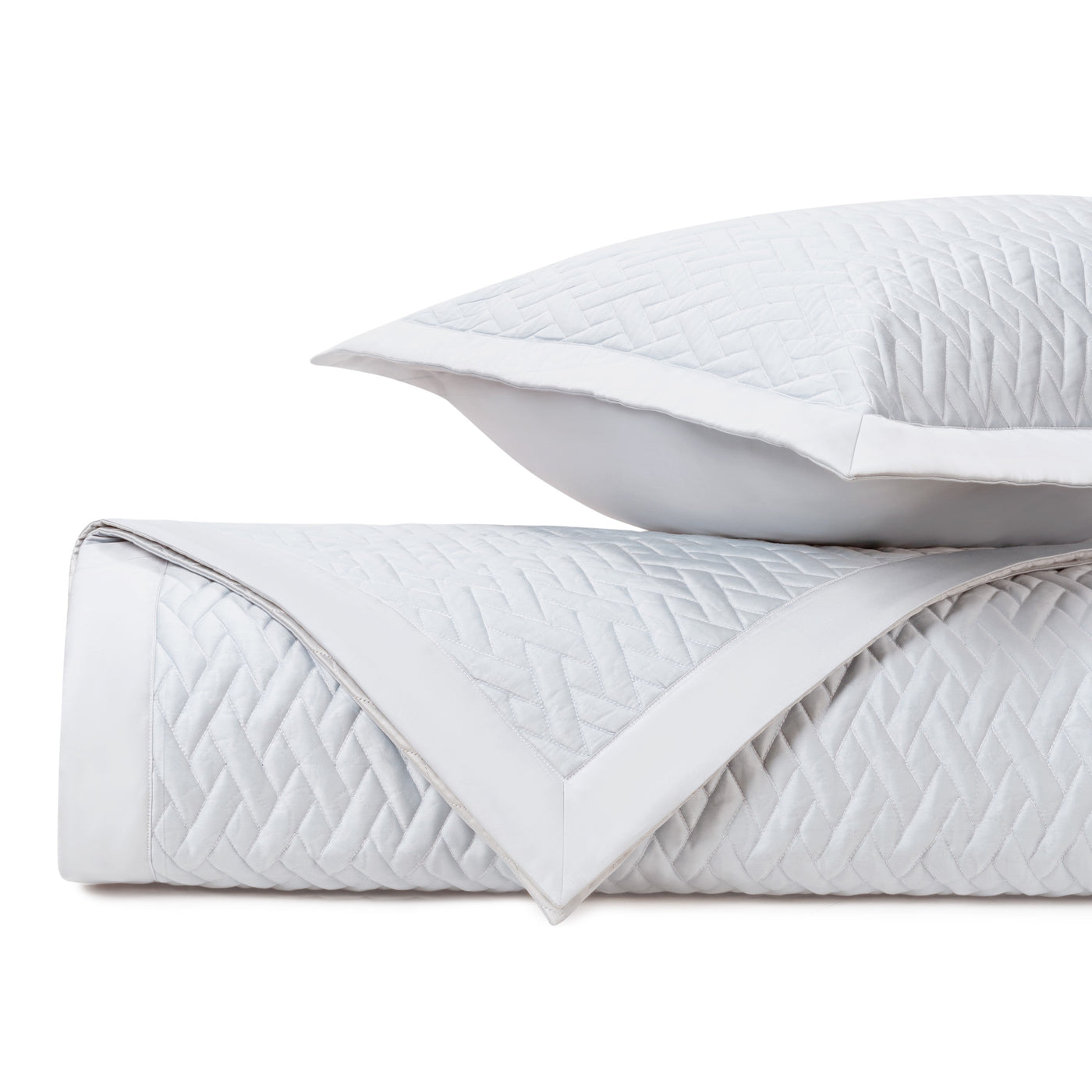 Close-up of white quilted cotton with diamond lattice stitching pattern and flanged edge detail.