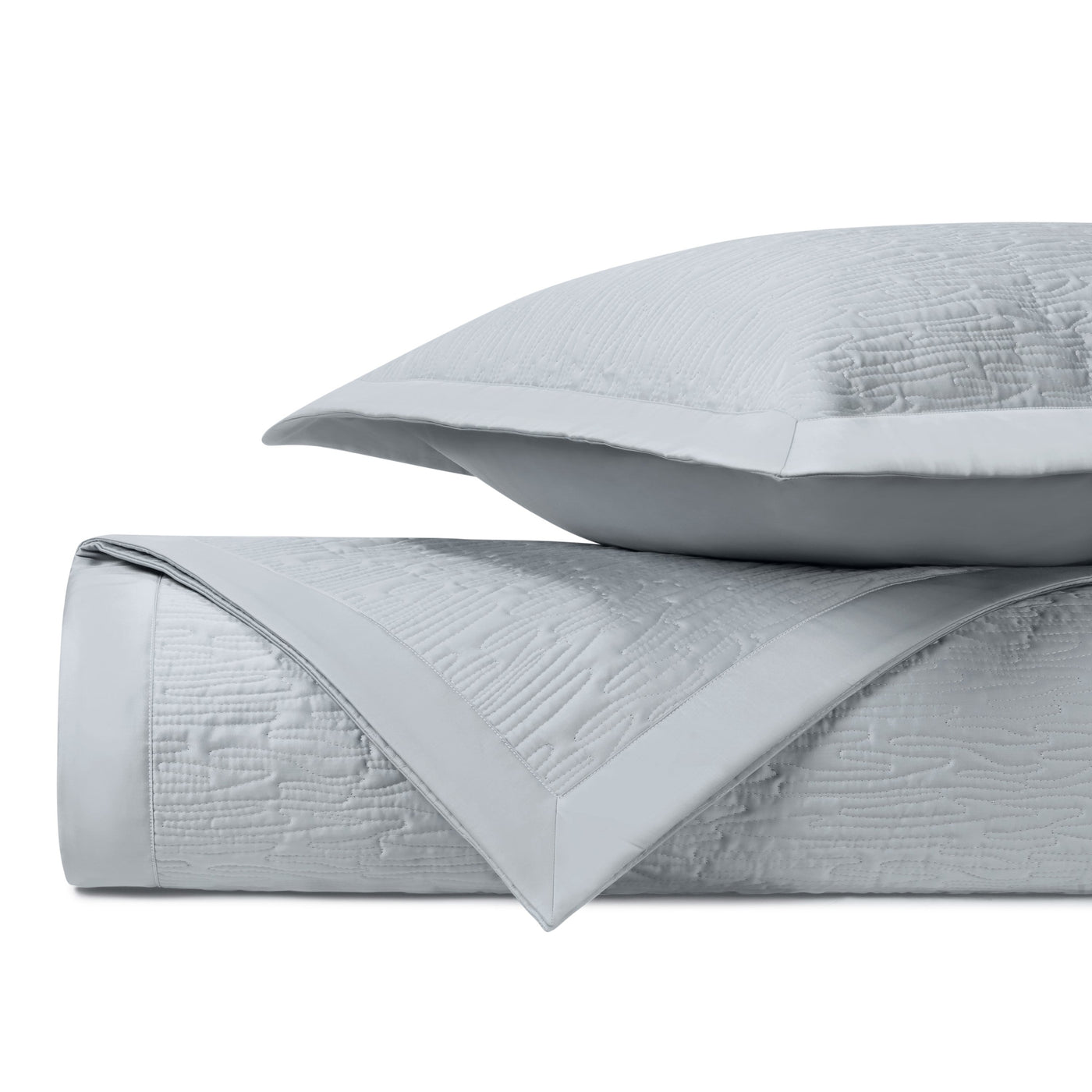 Close-up of silver matelassé wave-pattern quilted coverlet and sham with sateen border.