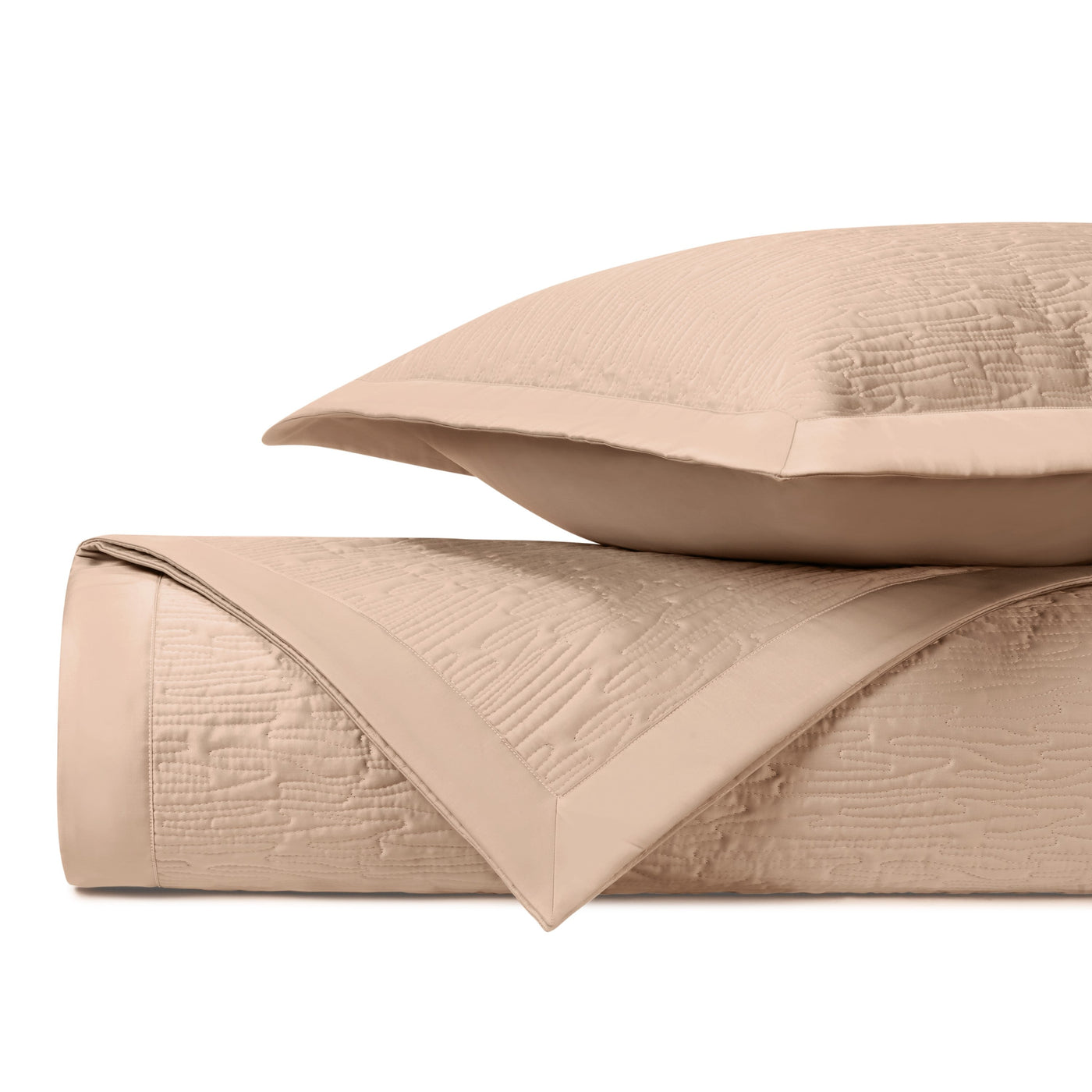 Close-up of Wave quilted coverlet set folded edge, showing blush matelassé texture and satin border.