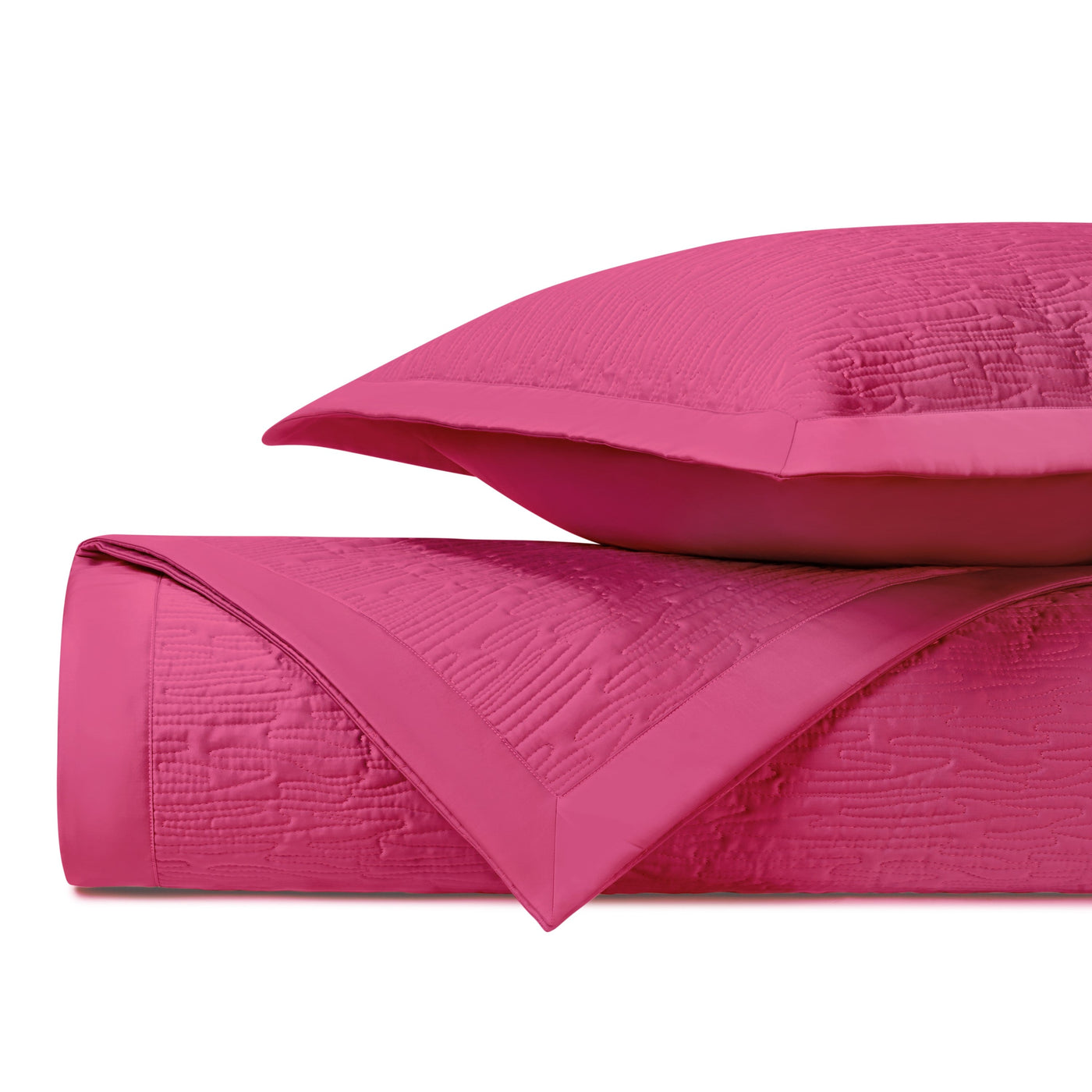 Folded fuchsia quilted coverlet showing textured wave pattern and flat border detail.