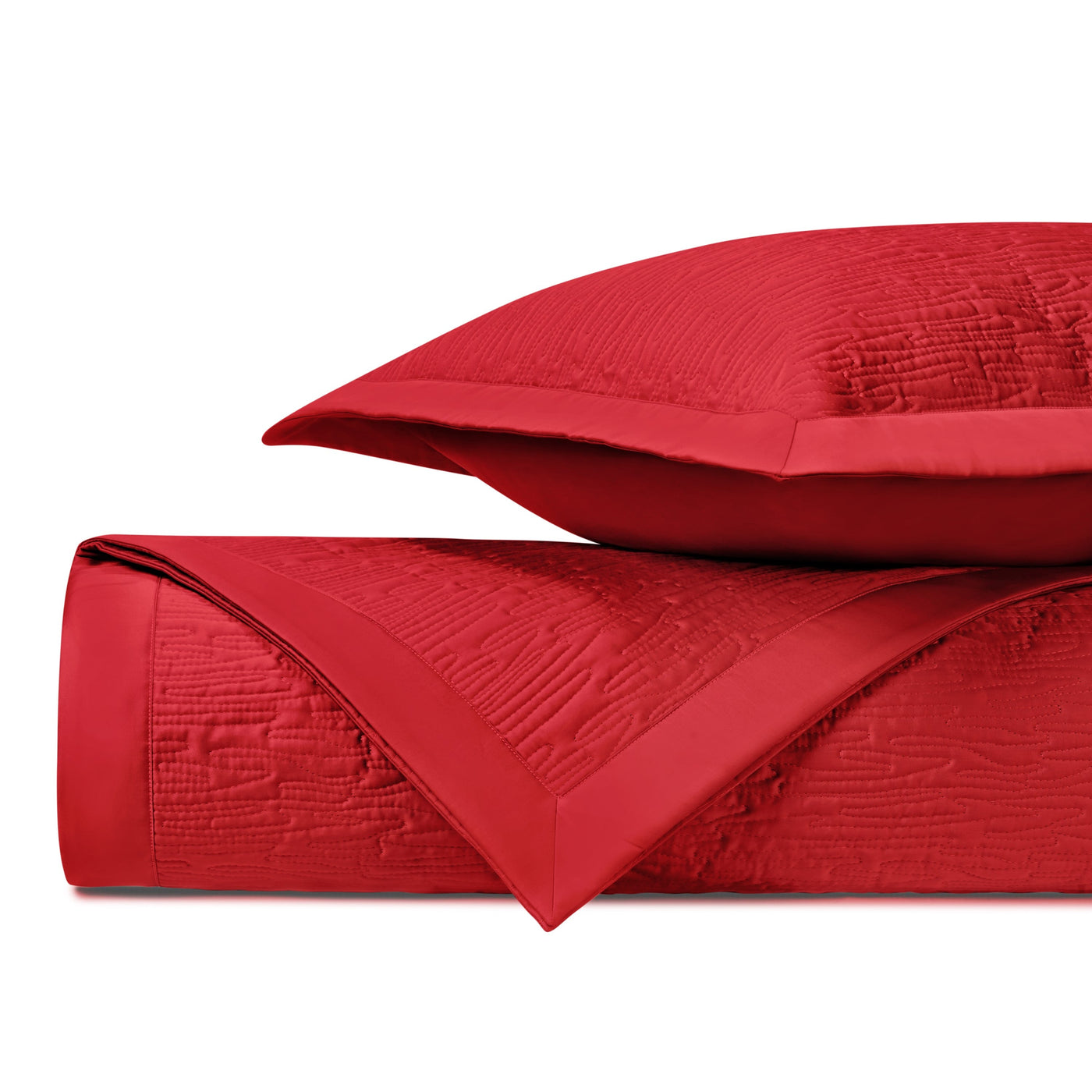 Close-up of crimson quilted matelassé fabric with wave-relief texture and satin border trim.