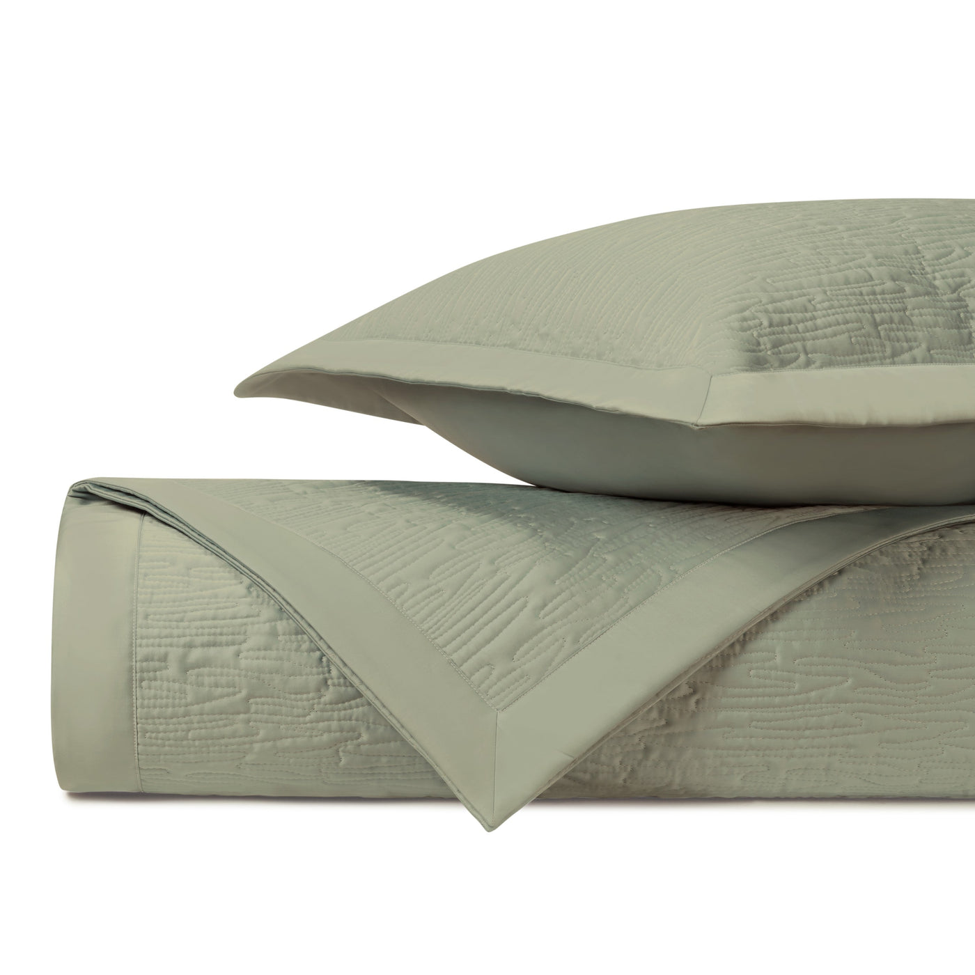 Sage green quilted coverlet folded beside a matching pillow sham, showing textured wave pattern.