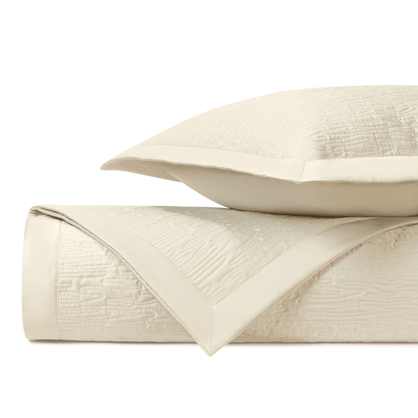 Ivory quilted matelassé folded stack showing wave-texture detail and border trim.