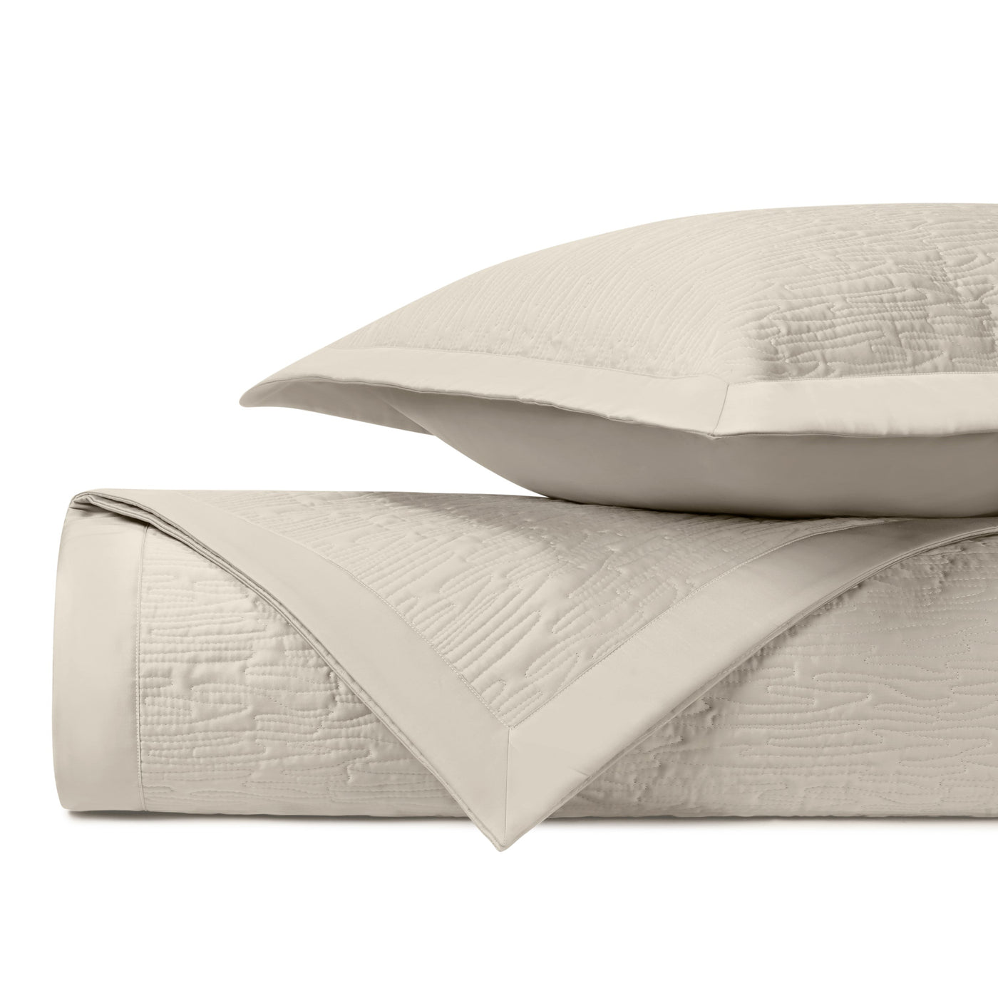 Ivory quilted coverlet folded to show textured wave pattern with matching sham.