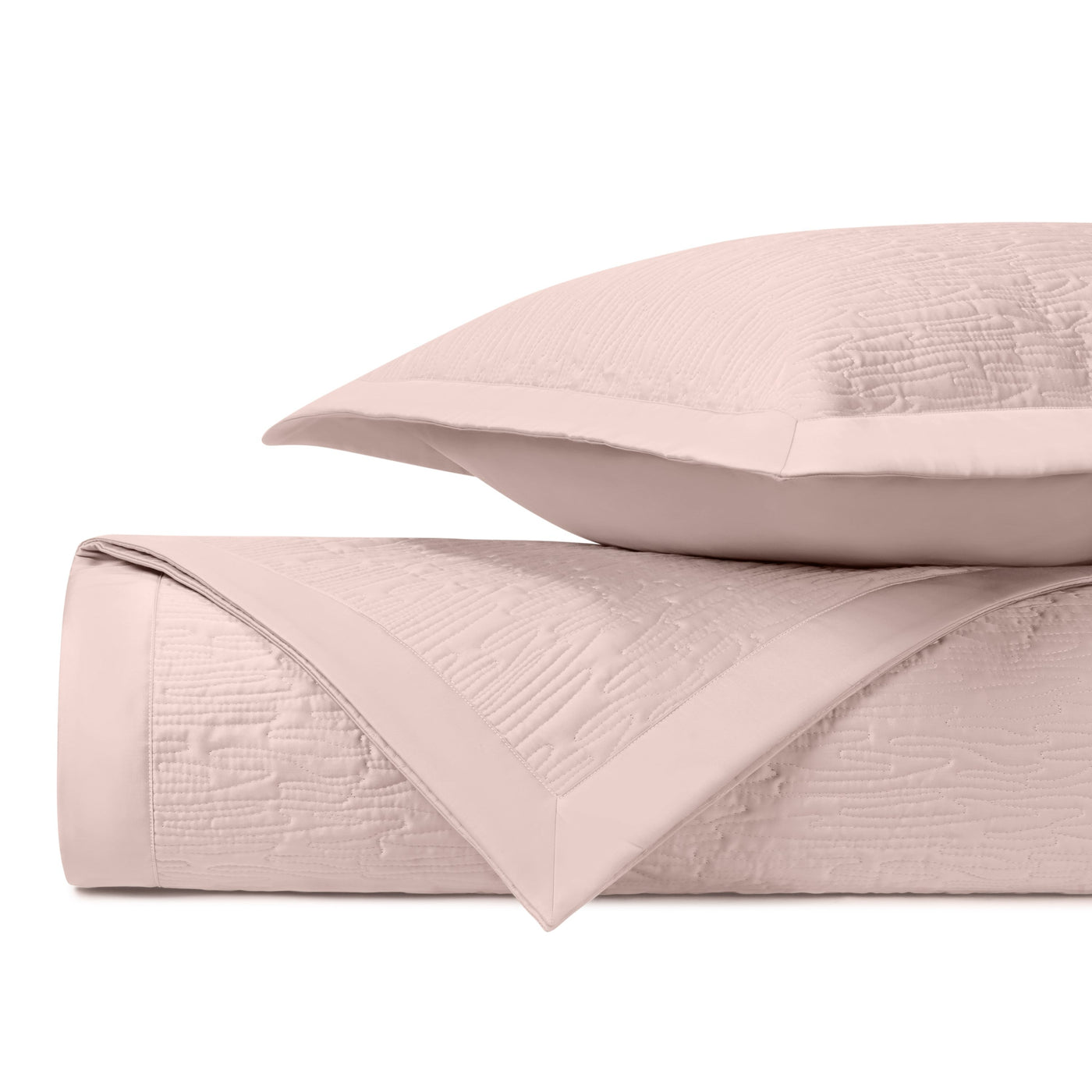 Close-up of blush matelassé quilted coverlet and sham with tonal border detail.
