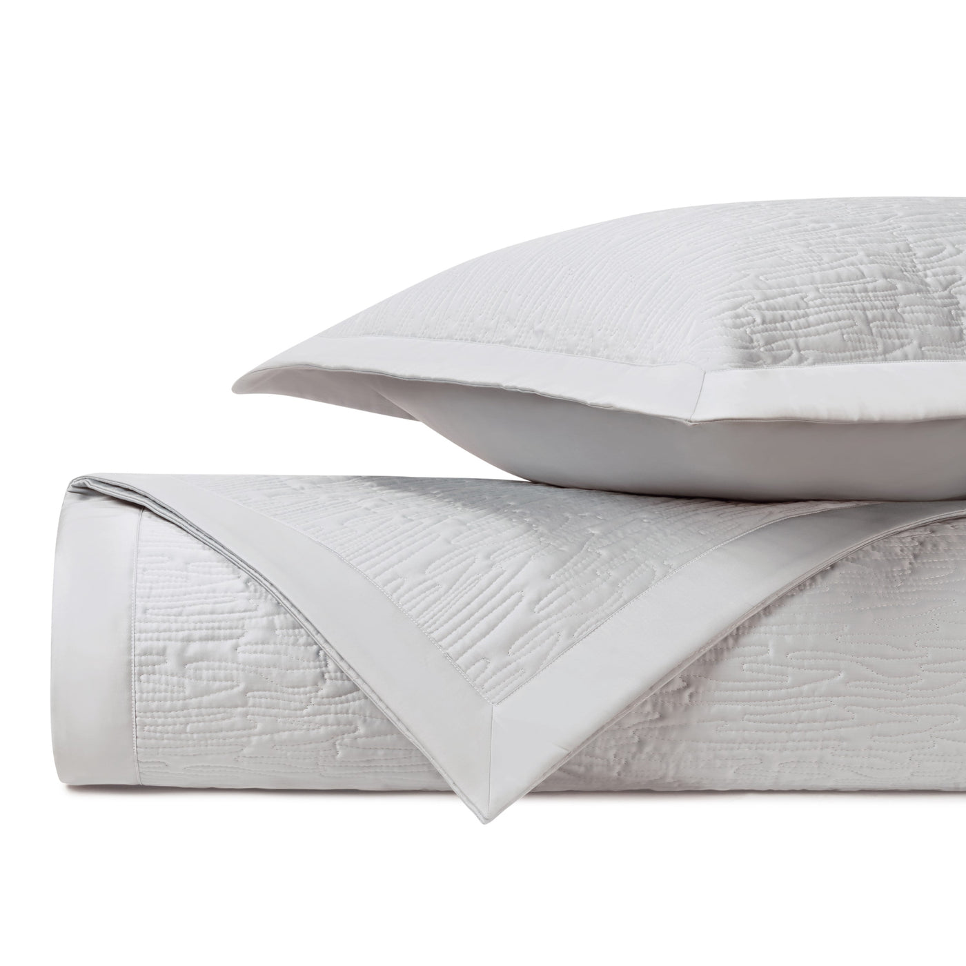 Close-up of ivory matelassé quilted fabric with wave-textured pattern and white border trim.