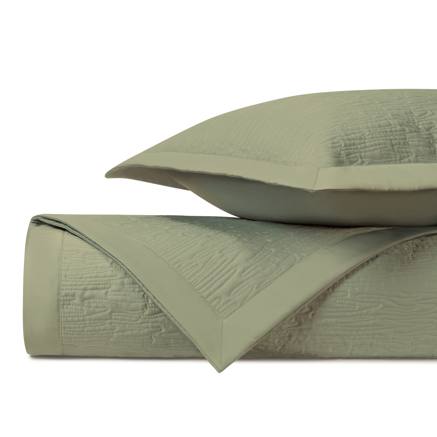 Close-up of sage green quilted coverlet and sham with textured wave pattern and border trim.
