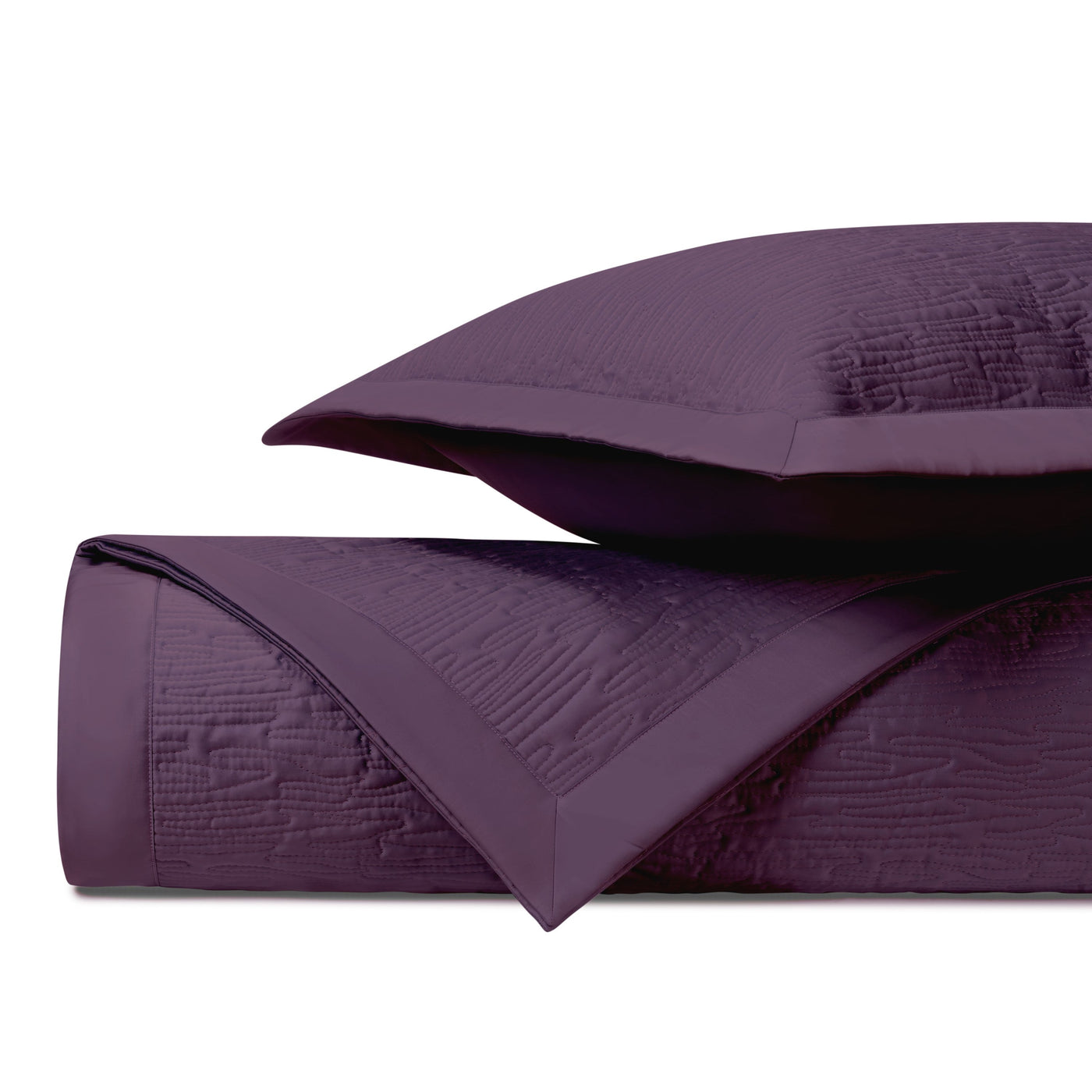 Close-up of amethyst quilted coverlet and sham showing textured wave stitching detail.