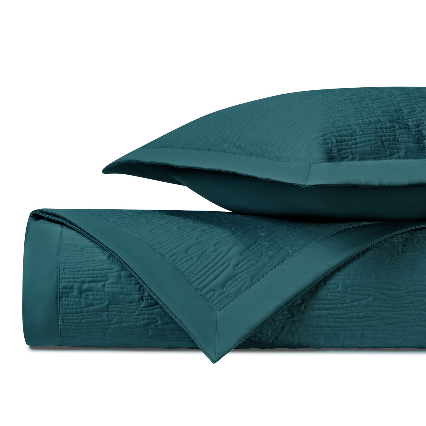 Teal quilted coverlet rolled and folded with matching sham, showing textured wave pattern detail.