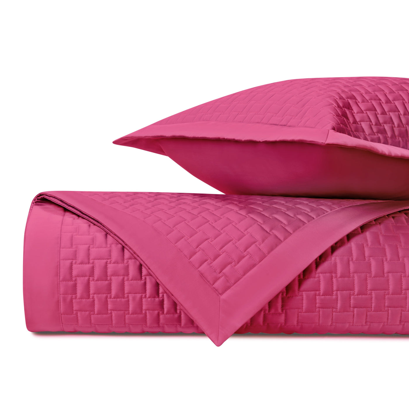 Fuchsia quilted coverlet rolled beside matching euro sham, basket-weave texture visible.