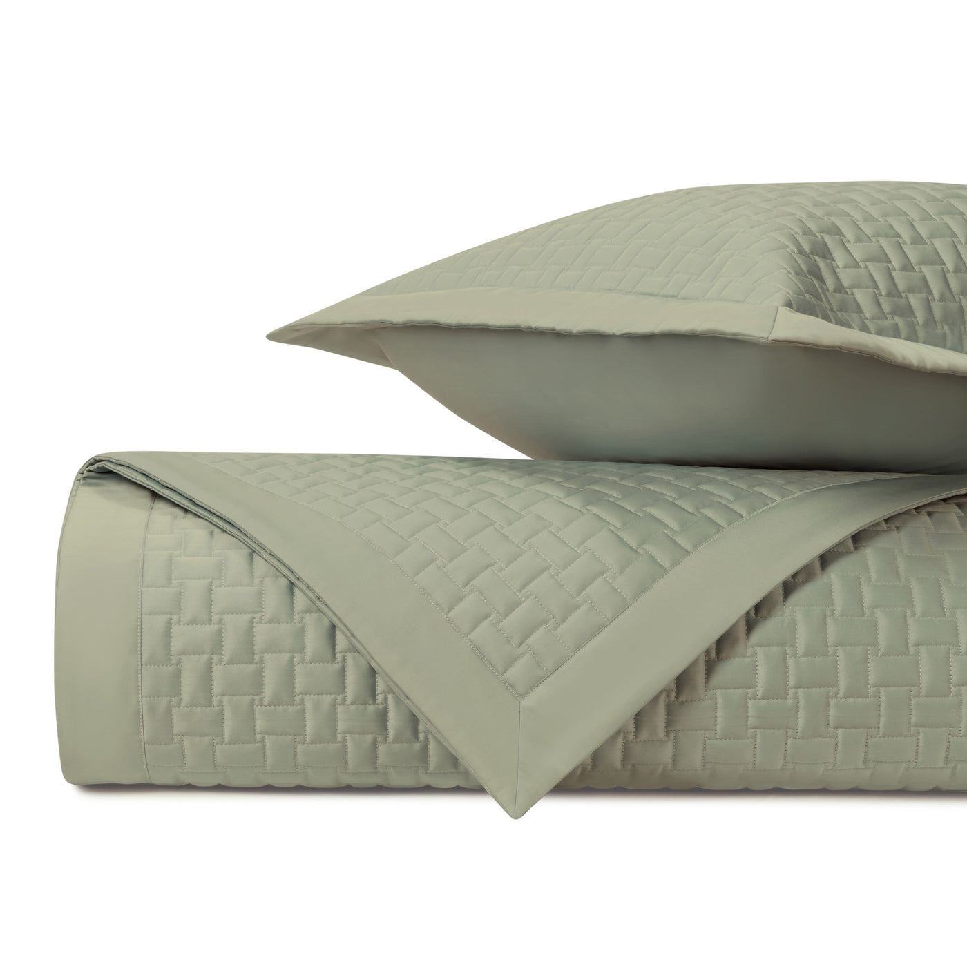 Sage green quilted coverlet and sham folded, showing basket-weave stitched texture detail.