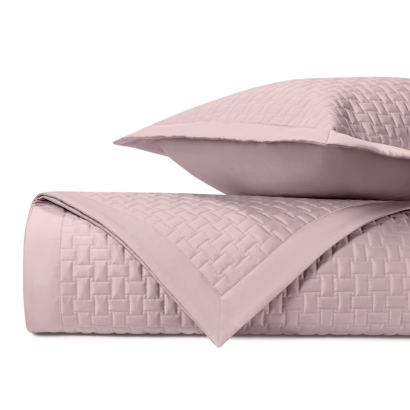 Close-up of blush quilted basket-weave texture on folded Home Treasures Wicker coverlet and sham.