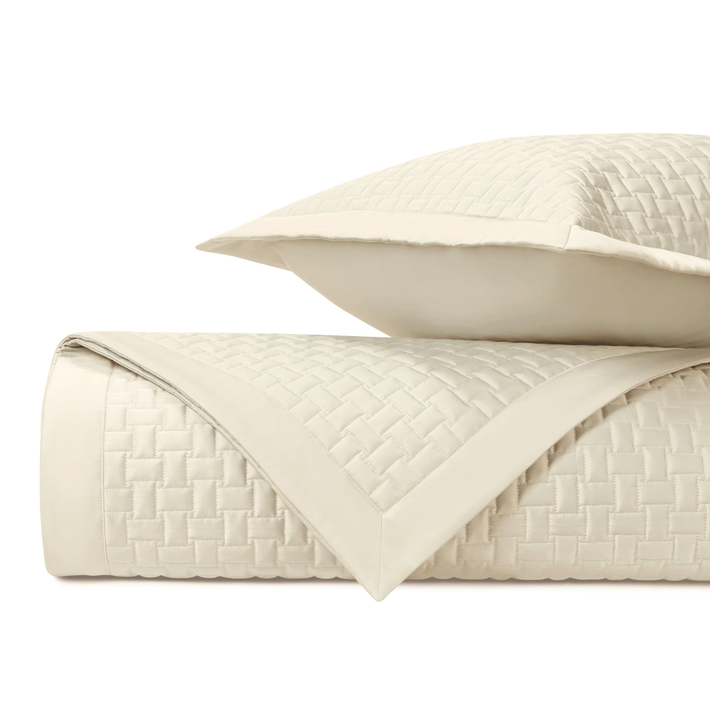 Ivory quilted coverlet rolled with sham, basket-weave texture and flat border detail.
