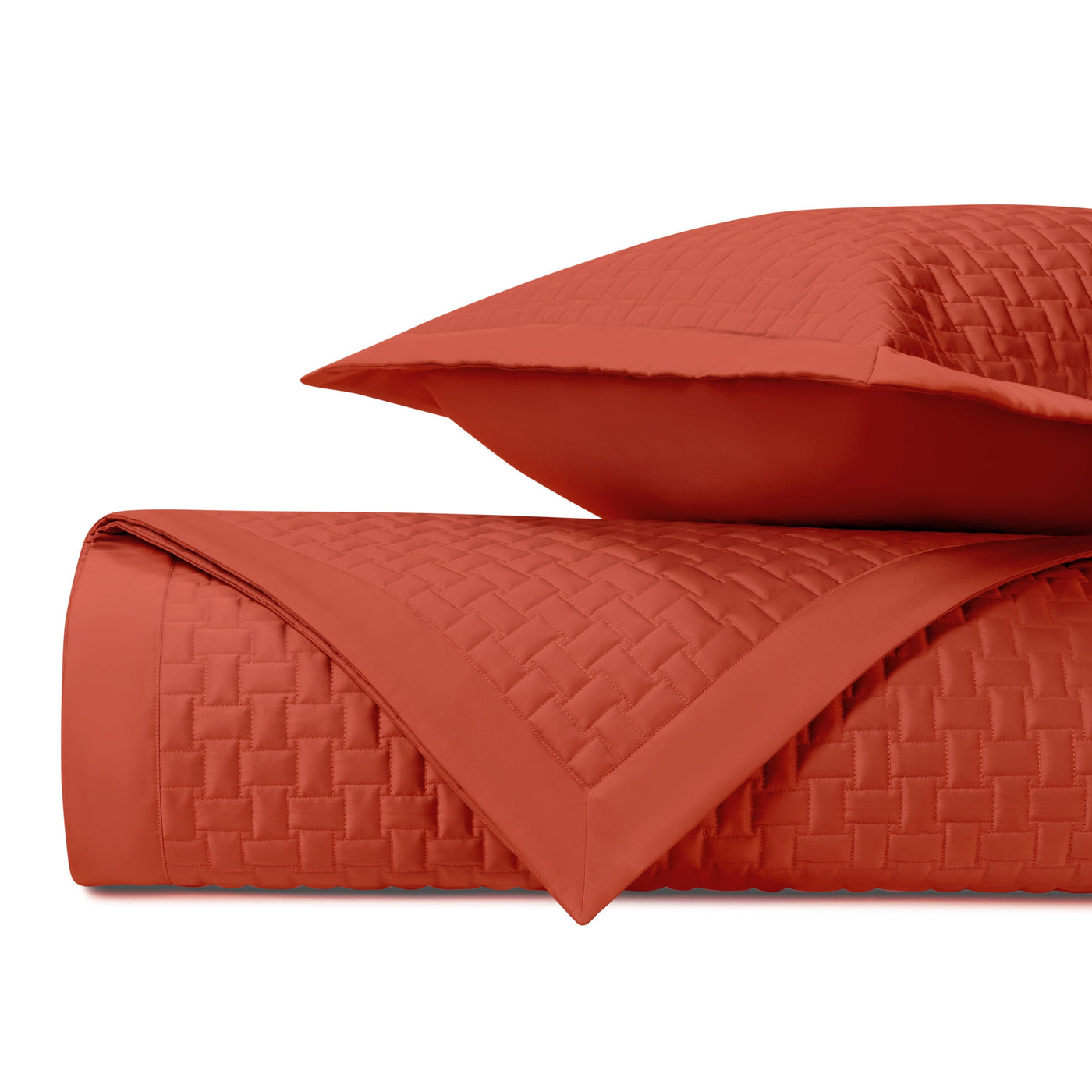 Close-up of coral quilted yardage with raised basket-weave texture and folded edge detail.