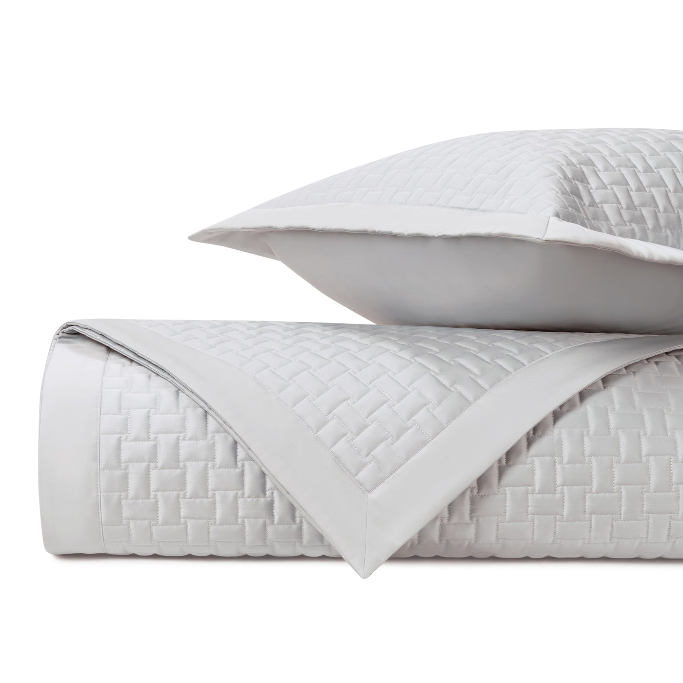 Close-up of ivory basketweave-quilted coverlet rolled with matching euro sham.