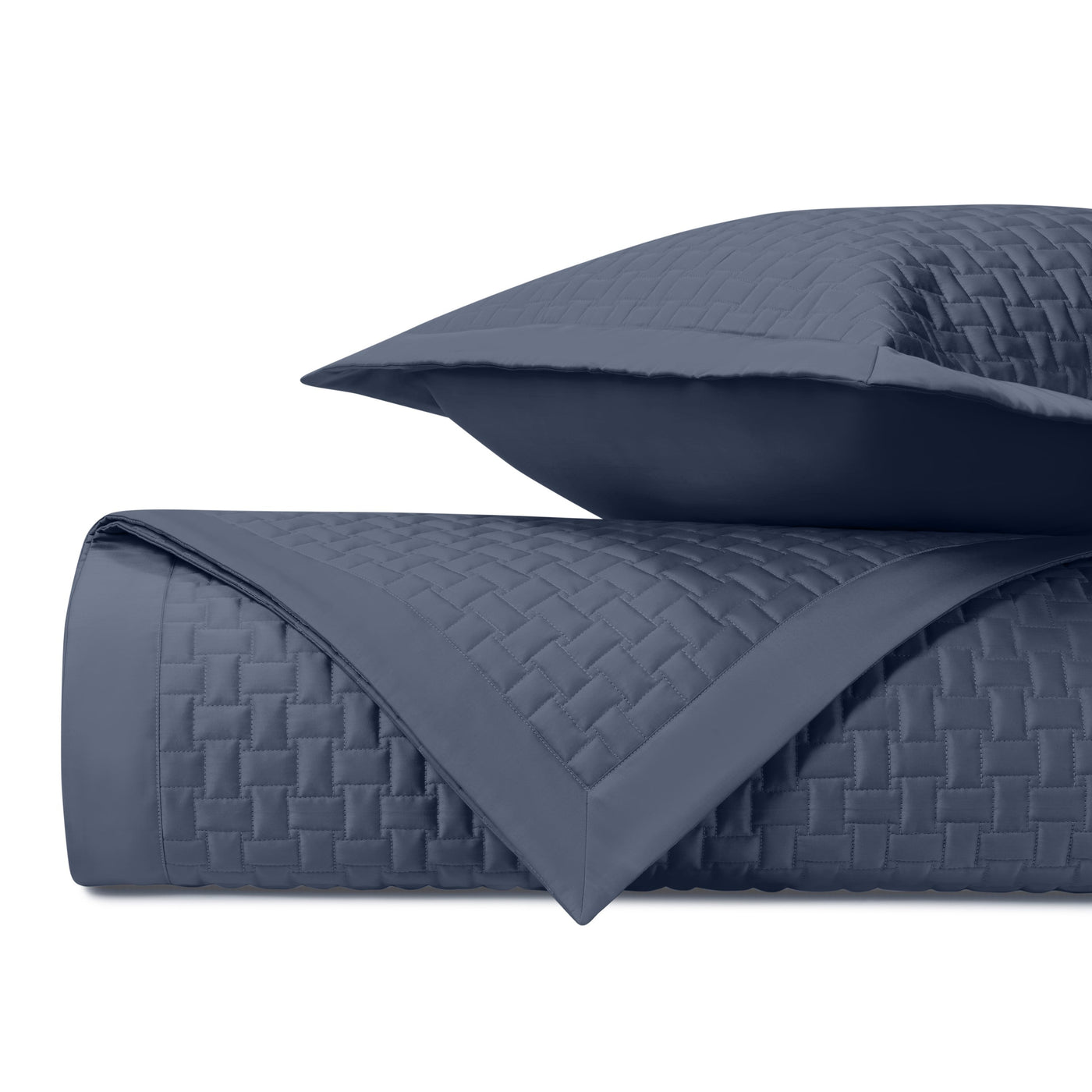 Close-up of navy blue quilted coverlet with wicker basket-weave stitching and matching sham.
