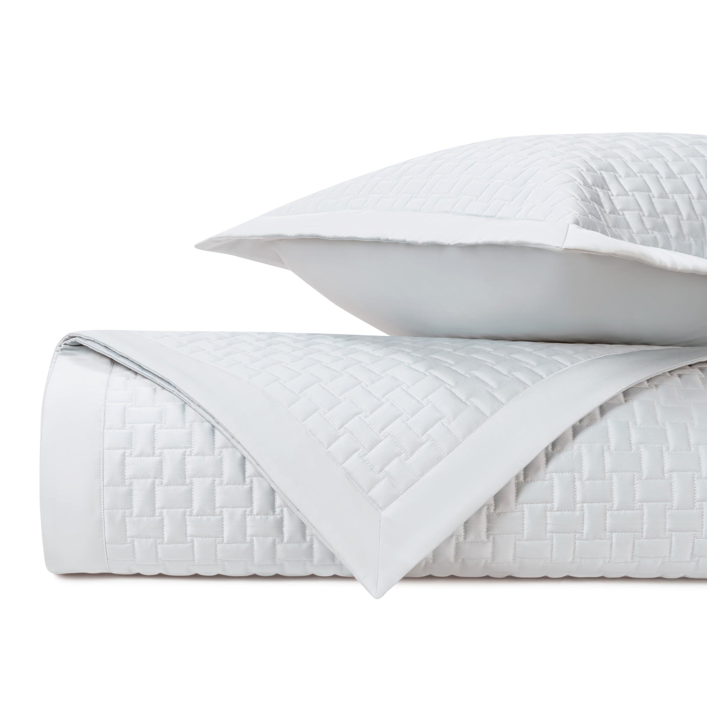 Close-up of white quilted coverlet with basket-weave texture and contrast border detail.