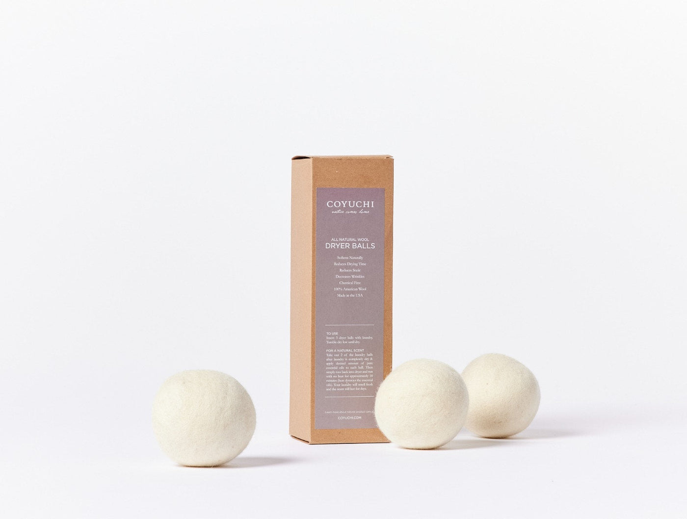 Coyuchi felt dryer balls in ivory beside kraft cardboard packaging on white background.