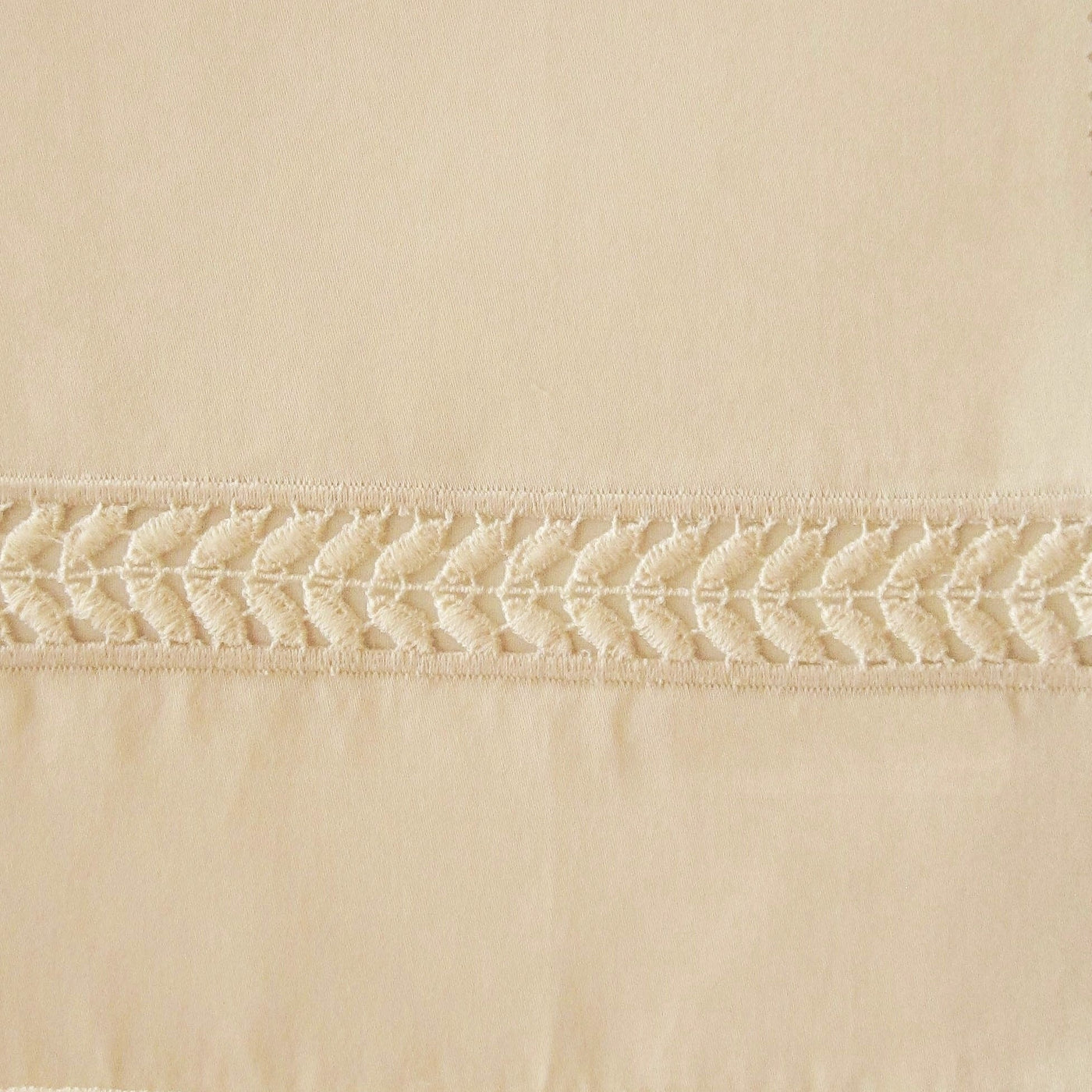 Close-up of champagne cotton sham's embroidered leaf-motif border trim.