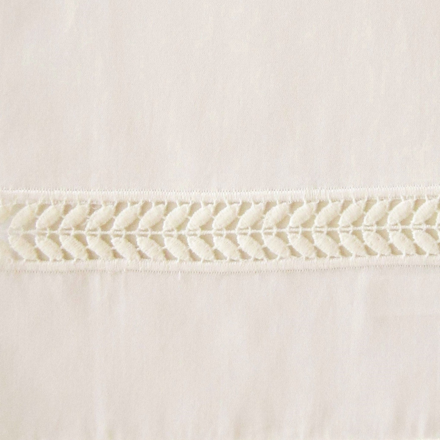 Close-up of ivory linen duvet cover with delicate woven wreath-pattern lace trim detail.