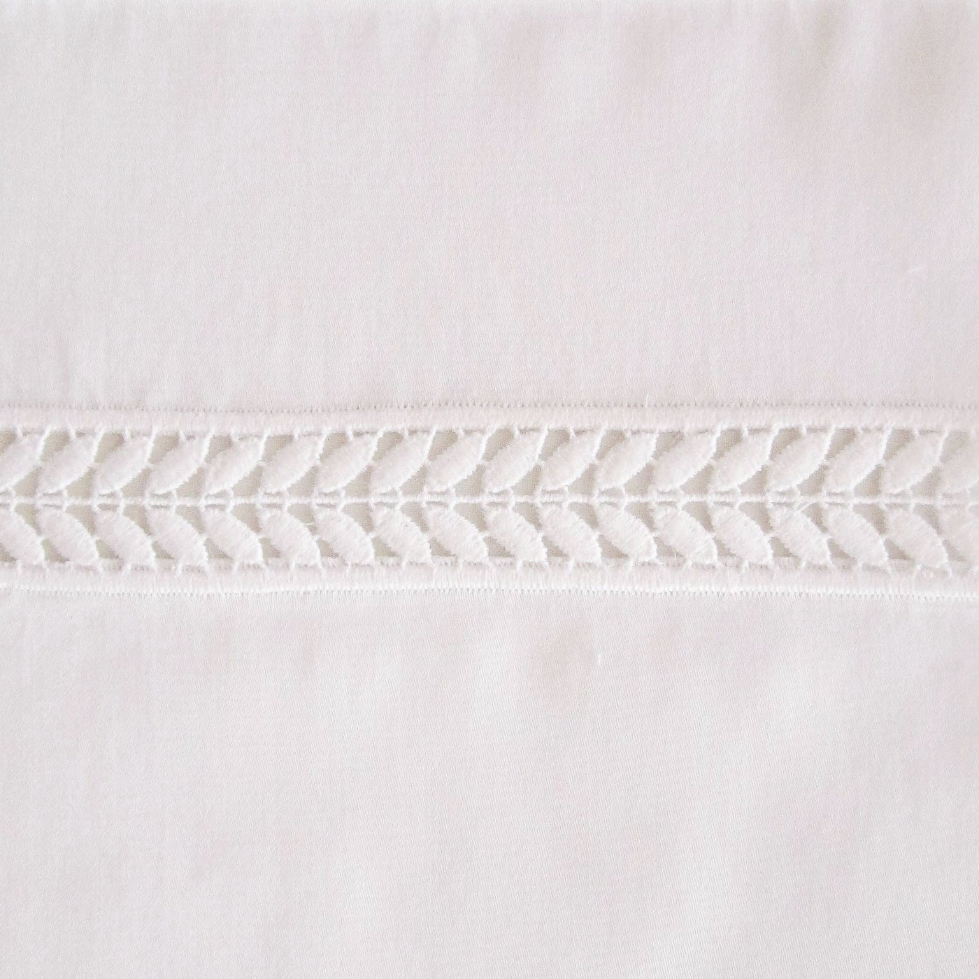 Close-up of ivory cotton duvet cover with delicate woven chevron lace trim detail.