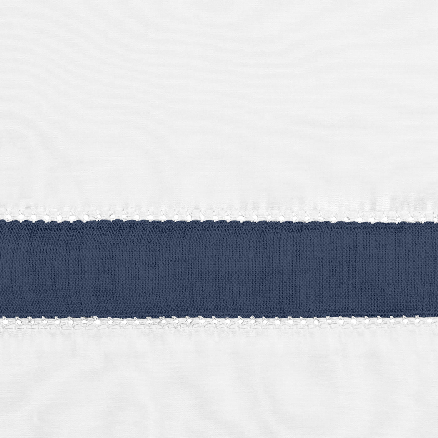 Close-up of navy grosgrain ribbon trim with white picot edging on crisp white linen.