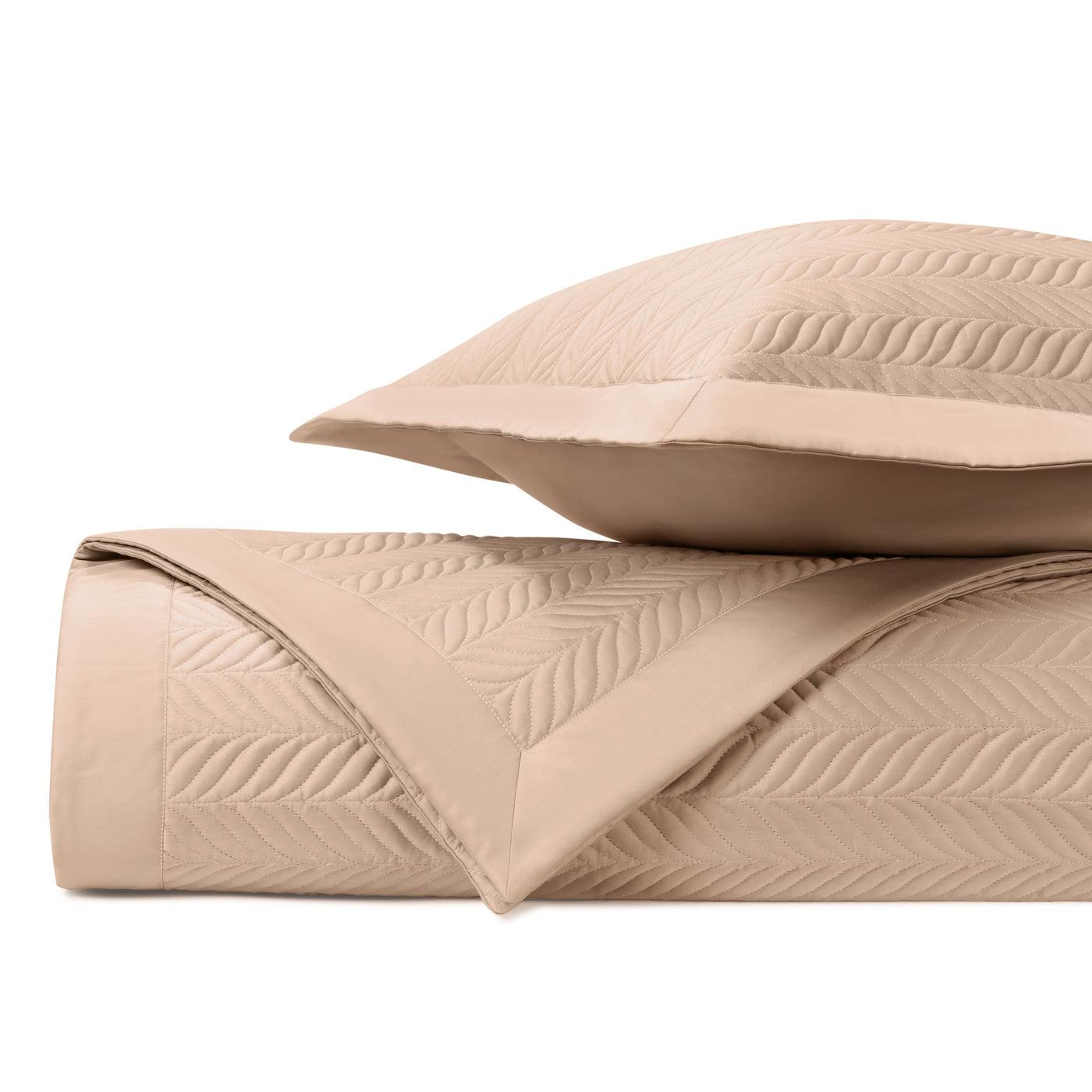 Close-up of quilted coverlet in champagne with embossed leaf pattern and matching sham.