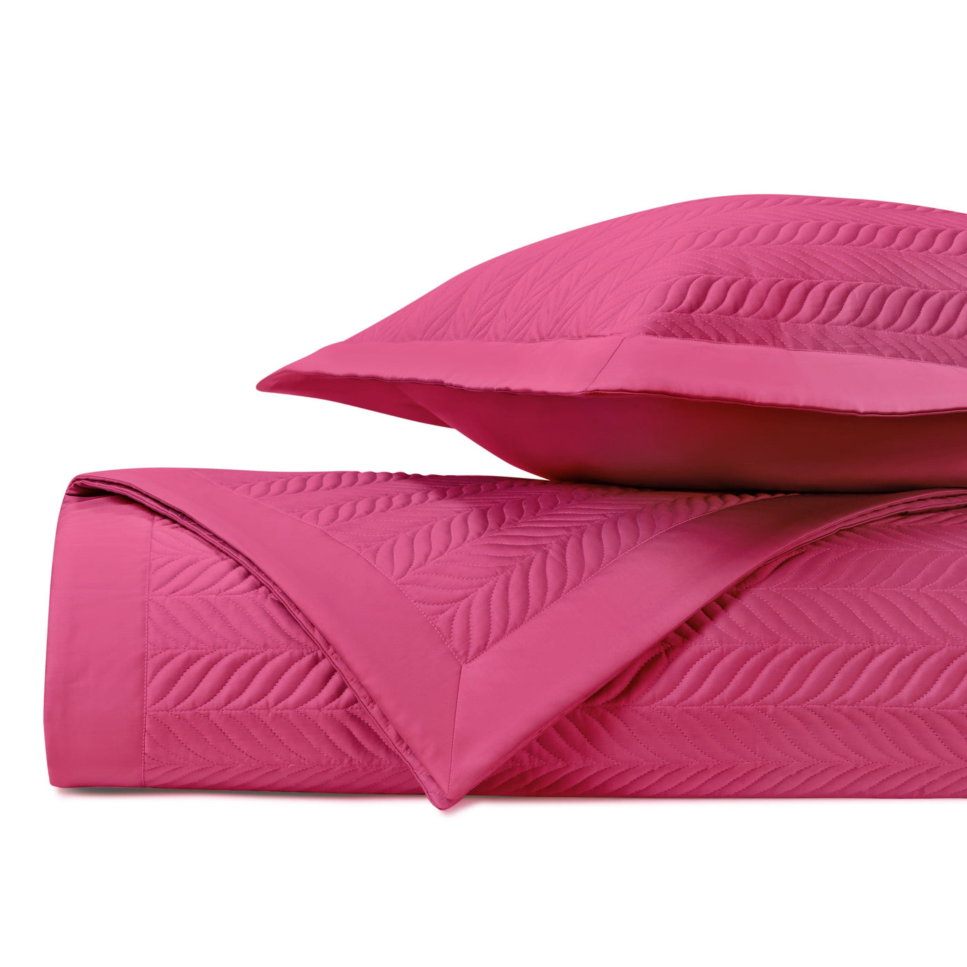 Close-up of fuchsia quilted coverlet with herringbone stitch pattern, folded beside matching sham.