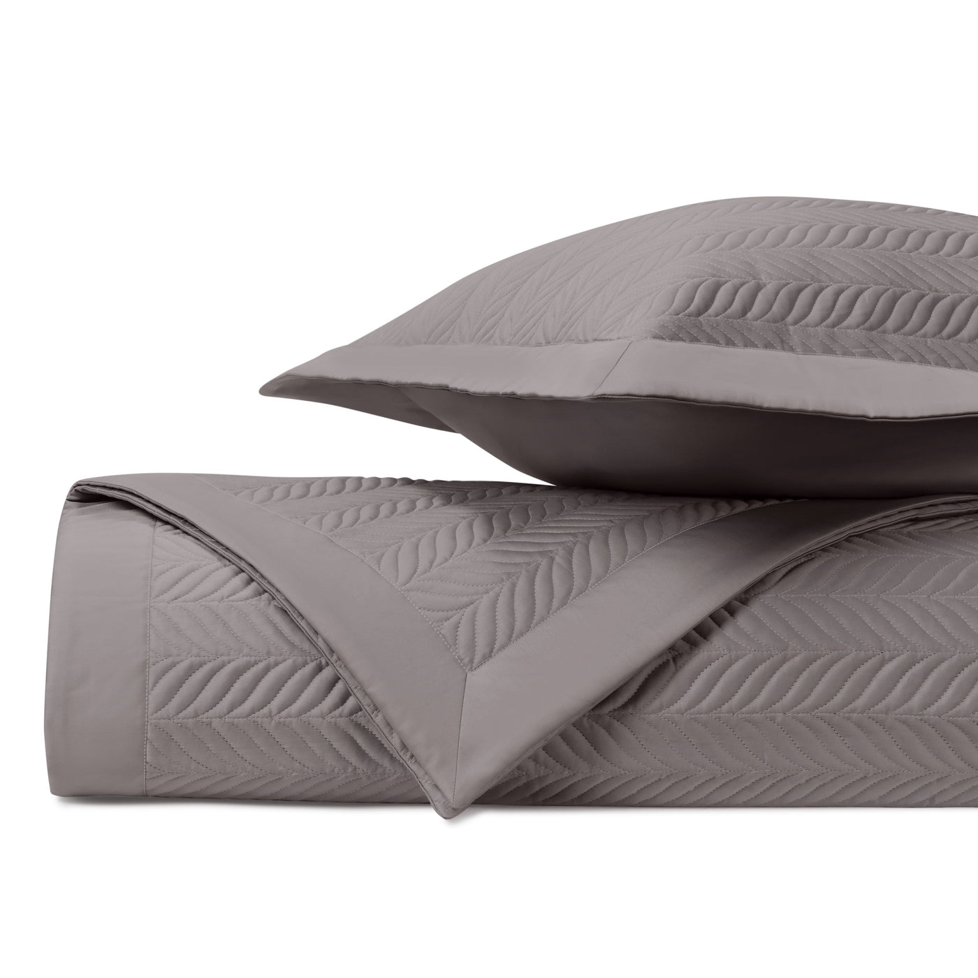 Close-up of smoke quilted coverlet fold showing embossed leaf pattern stitching detail.