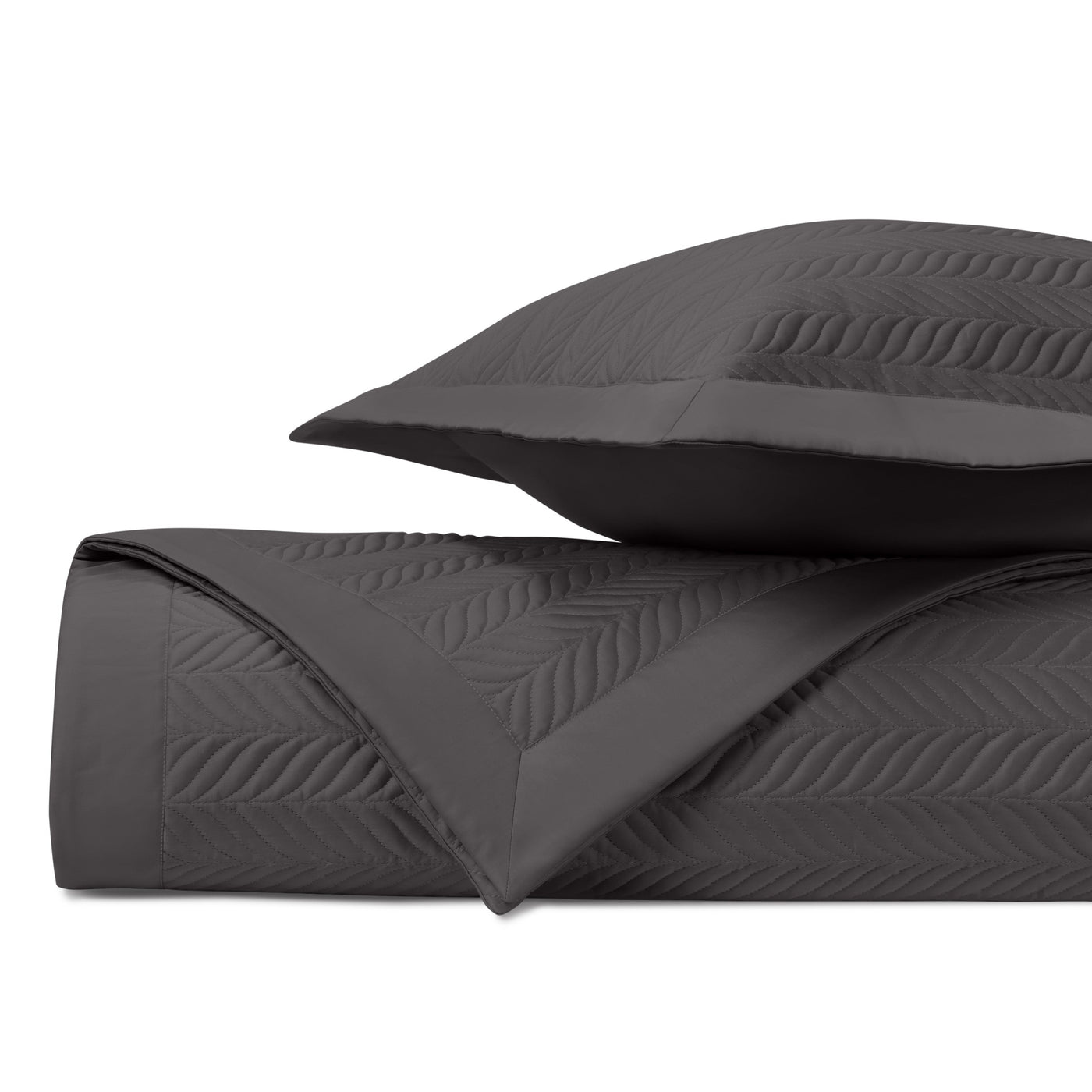 Folded charcoal quilted coverlet showing embossed leaf-pattern stitching with matching sham.