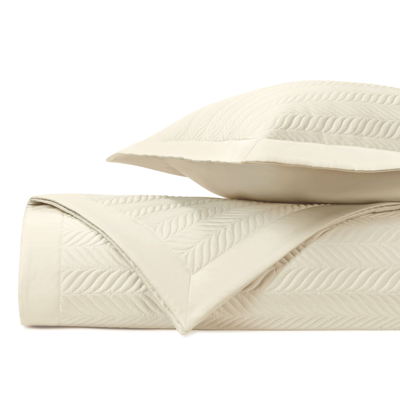 Close-up of ivory quilted coverlet and sham with raised herringbone stitching pattern.