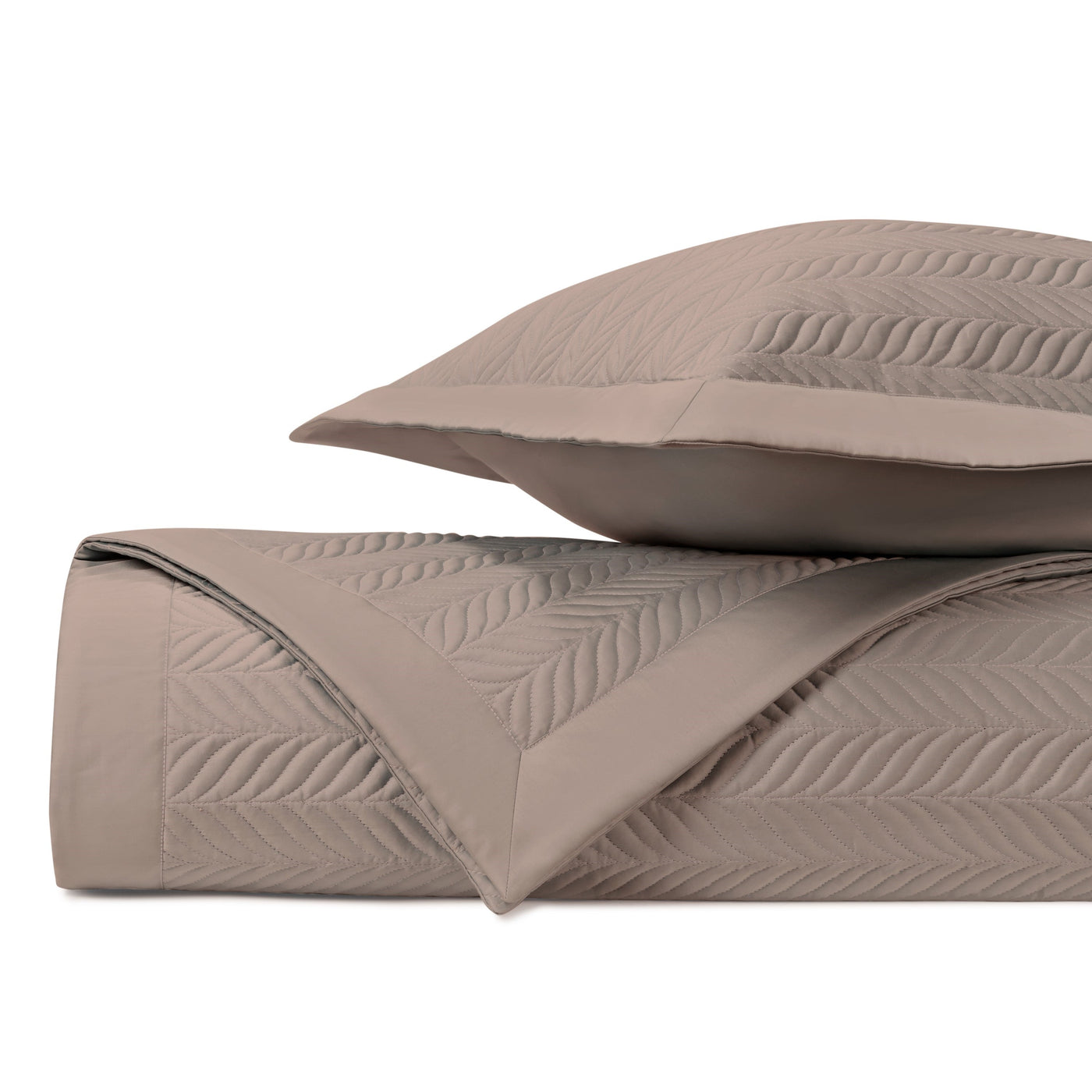 Close-up of Zurich quilted coverlet folded edge showing embossed leaf stitching in taupe.