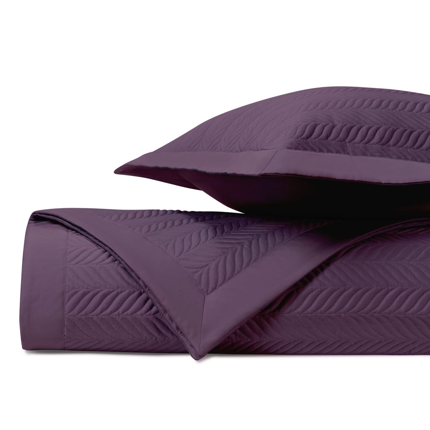Close-up of plum quilted coverlet with embossed chevron leaf stitching, folded with matching sham.