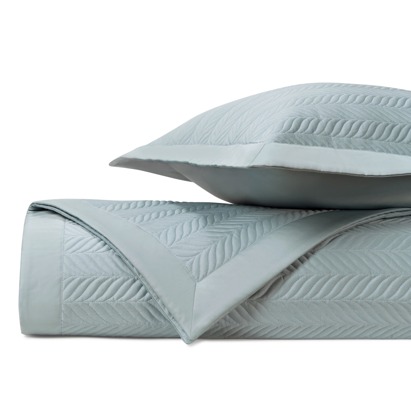 Close-up of mist blue quilted coverlet with leaf motif stitching and coordinating sham.