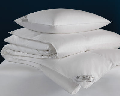 A stack of Sferra Buxton | Pillow sets is displayed against a dark blue background.