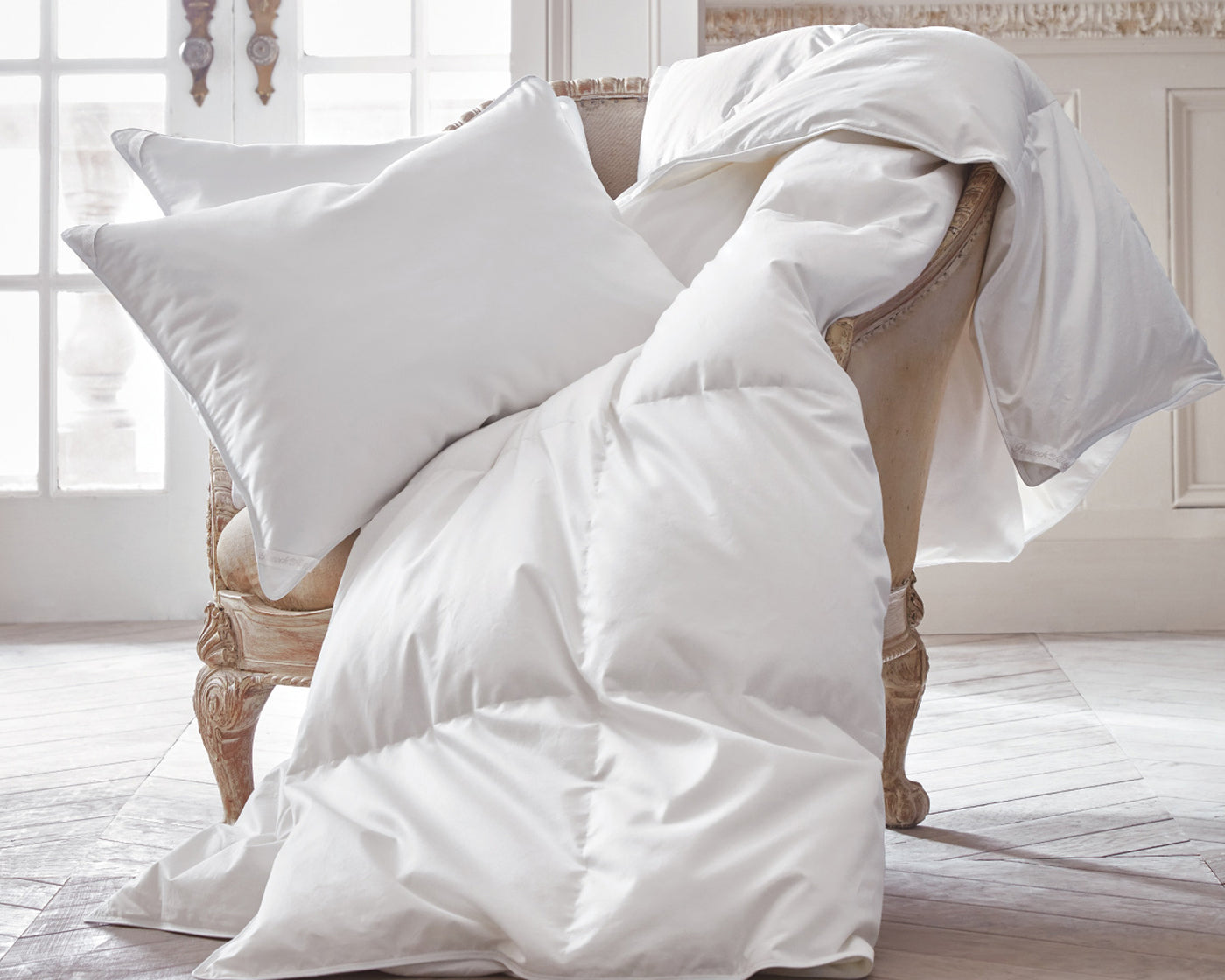 Peacock Alley white goose down duvet and pillow draped over chair